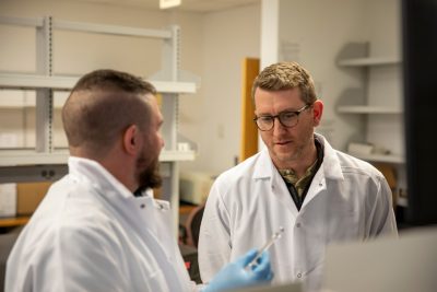 Two men in lab coats talk
