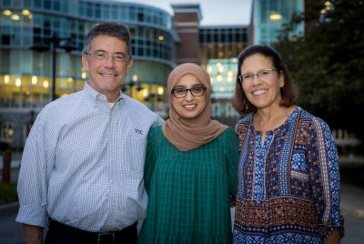 Woman wearing hijab flanked by male and female mentors.